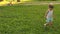 Little daughter and mom walk in park on lawn. Child walks on green grass. Mother and baby rest on lawn. Concept of a