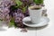 Little delicate elegant bouquet of spring flowers and a teacup on white wooden table, morning breakfast