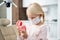 A little dentist in a medical mask inspecting artificial teeth