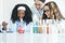Little diversity Caucasian and African black kids learning chemistry in school laboratory
