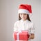 Little dreaming girl in Santa hat holding a gift