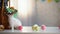 Little Easter bunny eating sweet cake, colored eggs and basket on table, food