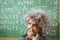 Little Einstein thinking in front of chalkboard