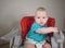 Little emotional newborn funny toddler boy sitting on feeding high chair. Baby facial expressions and goods packaging