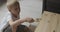 Little fair-haired boy carefully covers table with paint. Child helps with carpentry work.