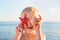 Little fair-haired boy playing with seastar and shell on sea background