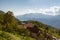 Little farm house with farmstead on th slops. Far mountains and white clouds background.