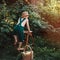 Little farmer in green overalls, standing in garden with happy face, in straw hat