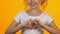 Little female kid showing heart sign with hands, smiling on camera, love concept