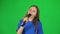 Little female singing into microphone on green screen at studio