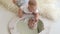 A little five-month newborn baby is playing with a mirror at home lying on bed.