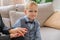 Little five-year-old boy in a shirt with a bow tie sits on the couch and holds his mothers hand