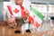 Little flag of Iran on table and flag of Canada put next to it by young woman