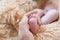 Little foot in hand. Father holding the legs of a newborn in his hands. Mom cares for the baby after taking a bath. Parents to