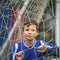 Little football player behind the football goal. Sport.