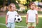 Little football team: toddler girl with soccer ball and boy in sports uniform standing at football field together