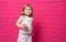 Little funny blonde girl in white shirt eats donut on pink background