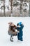 Little funny boy with her mother skating in the park. Play ice hockey with stick and goal. Outdoor. Winter sport.