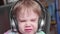 A little funny boy sits in a chair and listens to music through headphones. Face close up