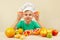 Little funny boy with two slices of grapefruit at table with fruits