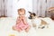 Little funny Caucasian girl the child sits at home on the floor on a light carpet with the best friend of the half-breed dog with