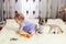 Little funny Caucasian girl the child sits at home on the floor on a light carpet with the best friend of the half-breed dog with