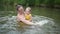 Little funny cute blonde girl child toddler in yellow bodysuit laughing learns swim outside at summer lake. Plus size