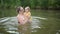 Little funny cute blonde girl child toddler in yellow bodysuit laughing learns swim outside at summer lake. Plus size