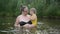 Little funny cute blonde girl child toddler in yellow bodysuit laughing learns swim outside at summer lake. Plus size