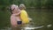 Little funny cute blonde girl child toddler in yellow bodysuit laughing learns swim outside at summer lake. Plus size