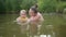 Little funny cute blonde girl child toddler in yellow bodysuit laughing learns swim outside at summer lake. Plus size