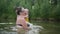 Little funny cute blonde girl child toddler in yellow bodysuit laughing learns swim outside at summer lake. Plus size