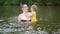 Little funny cute blonde girl child toddler in yellow bodysuit laughing learns swim outside at summer lake. Plus size