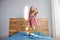 Little funny little child girl in motion jumping on bed alone flying in air feeling joy