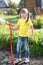 Little gardener girl watering with hosepipe