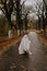 little ghost standing on the road in red boots. Autumn halloween