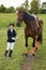 Little gir jockeyl lead horse by its reins across country in professional outfit