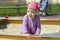 Little girl 1 year old in dress and scarf looks to the side cheerfully. horizontal close-up