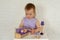 Little girl 1 years playing with doll house furniture. Cute baby girl in violet dress. Violet style