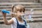 A little girl of 3-4 years old with blonde hair blows soap bubbles on the street. Children`s entertainment in the summer and holid