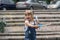 A little girl of 3-4 years old with blonde hair blows soap bubbles on the street. Children`s entertainment in the summer and holid