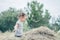 Little girl 3-4 years old jumps and plays in hay stack, throwing it up. Motion blur