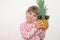 Little girl 3 years old, holding a pineapple in his hands in glasses