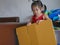 Little girl, 3 years old, moving a cardboard box, preparing to build something by herself, at home