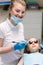 Little girl in 3D glasses sitting on destal chair at the office and have yearly checkup. Dentist with assistant