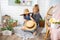 Little girl of 4-5 years old is playing with straw hats on veranda of house with her mother in arms. Laughter, happiness, joy,
