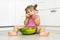 little girl 4 years old with appetite eats watermelon with a spoon sitting on the floor at home