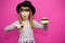 Little girl 6-7 years old in black hat with shoked face hold credit bank card isolated on pink. Childhood lifestyle concept