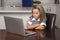 Little girl 6 to 8 years old sitting at home kitchen enjoying with laptop computer concentrated watching internet cartoon movie