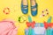 Little girl accessories. Pink bag with colorful dress, circlet, hair ties and shoes on yellow background. Top view